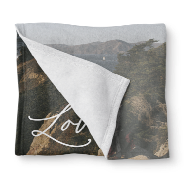 Personalized sweatshirt blanket featuring the word love written in cursive and mountains in the background