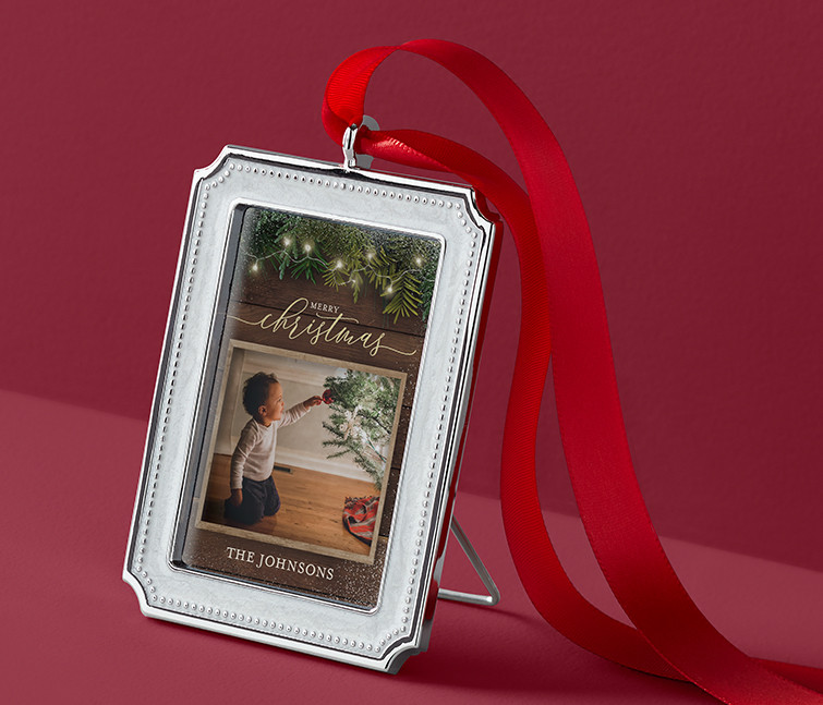 A personalized picture frame ornament that says Merry Christmas with a picture of a child touching a Christmas tree