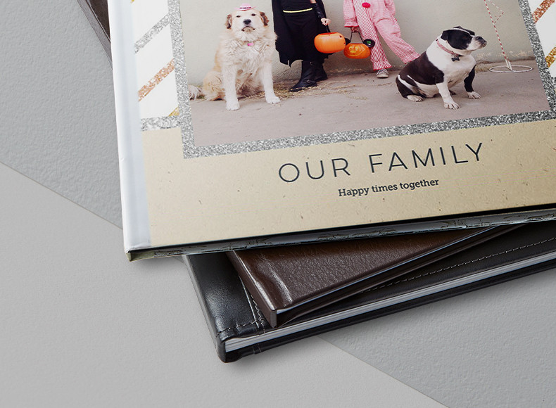 A stack of hardcover and leather photo books with a picture of a family and dogs on the cover